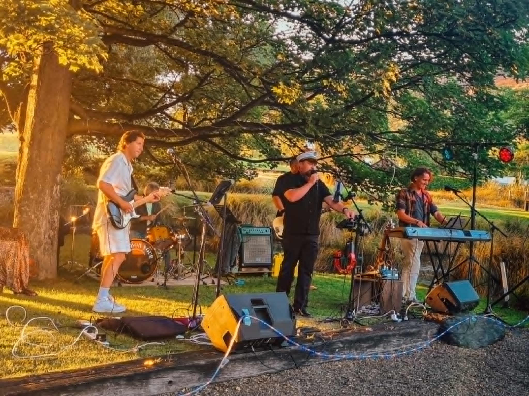 Live outdoor performance by a vibrant rock band under string lights, energizing a crowd at a nighttime event � perfect for weddings, parties, and special occasions in Queenstown and Central Otago.